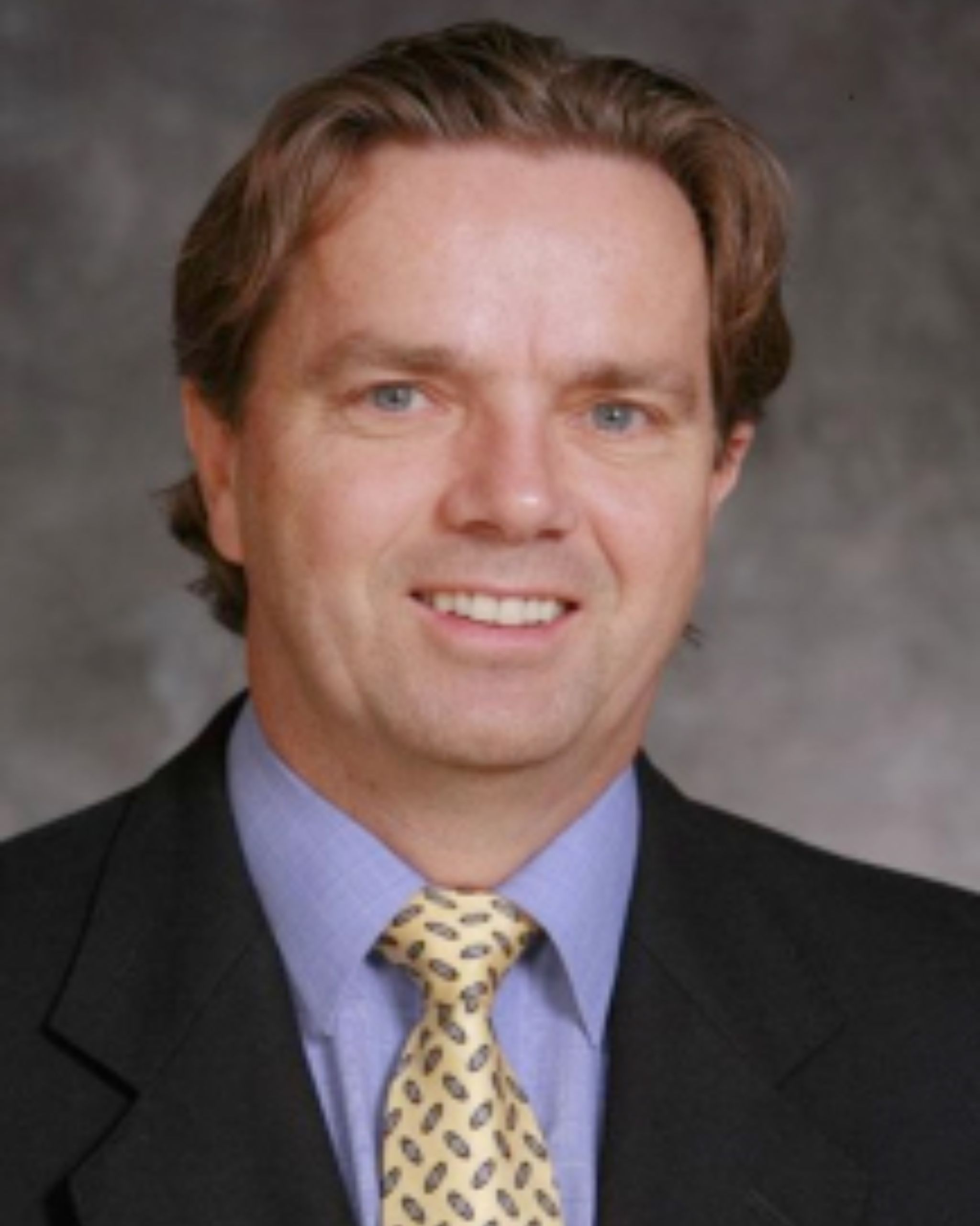 Man in suit and glasses, smiling.