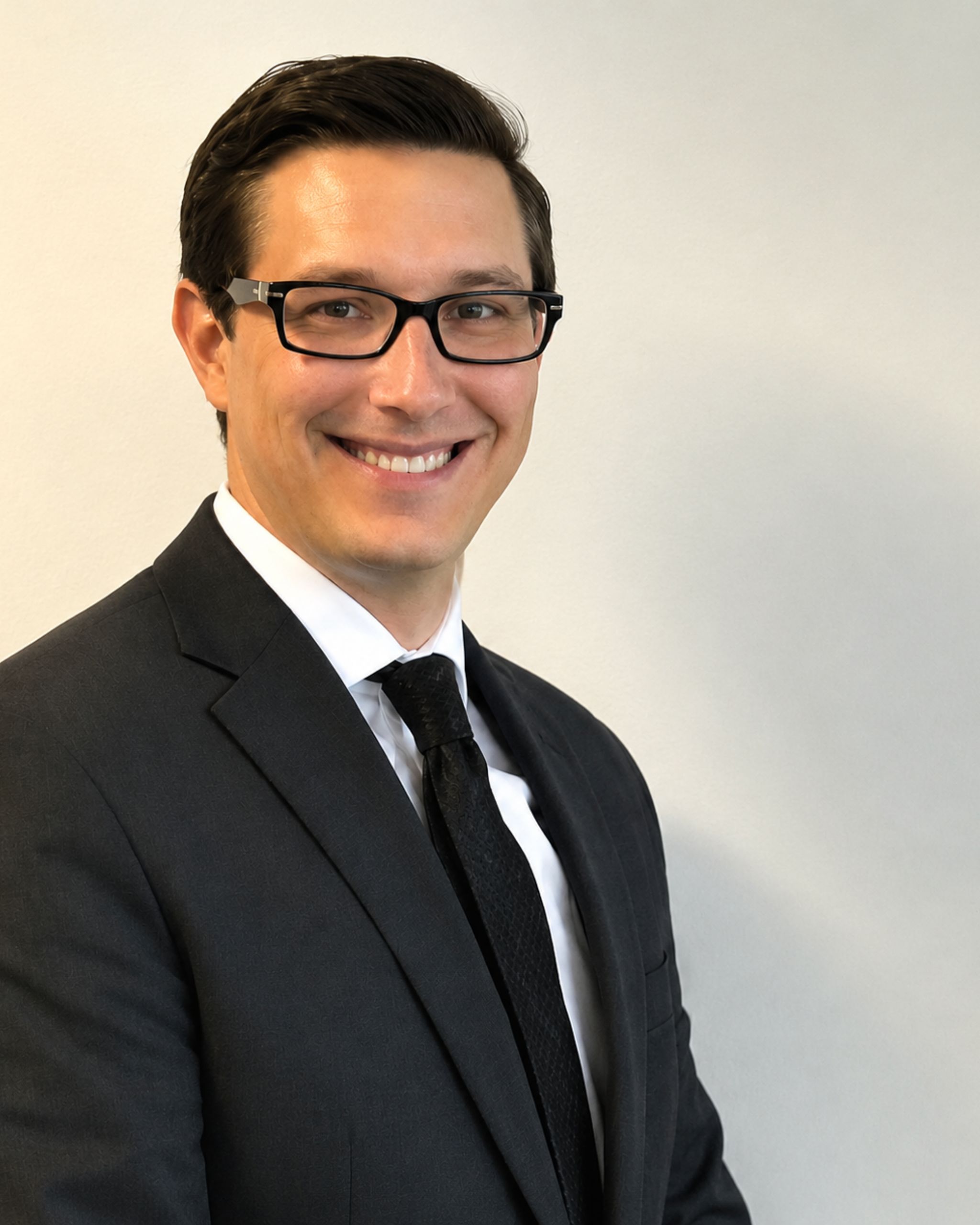 Man in suit and glasses, smiling.