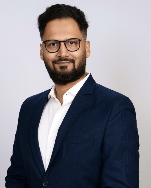 Man in suit and glasses, smiling.